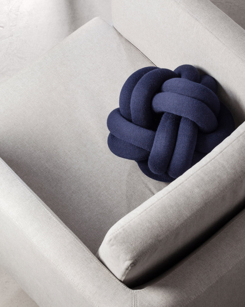 Navy blue knotted pillow on a light gray sofa