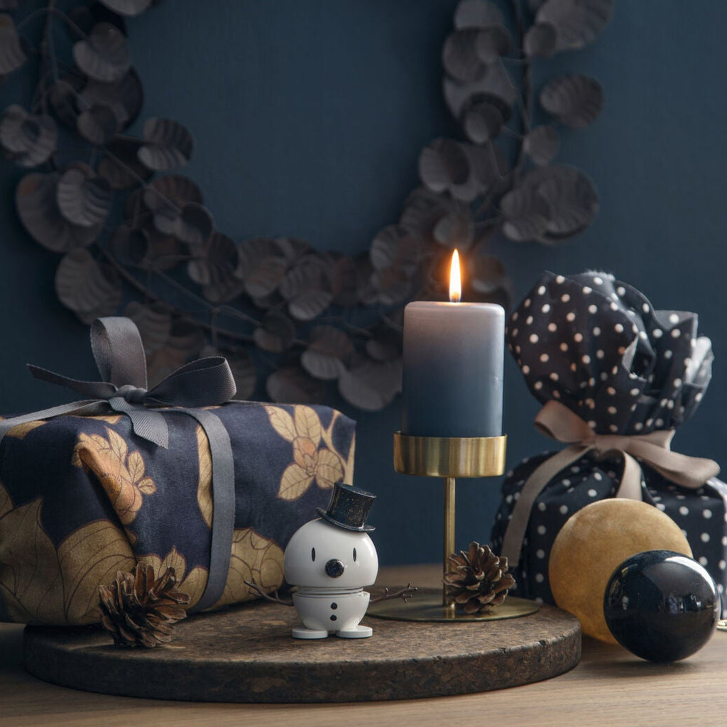 Decorative setup with a candle, wrapped gift, and decorative items on a wooden surface.