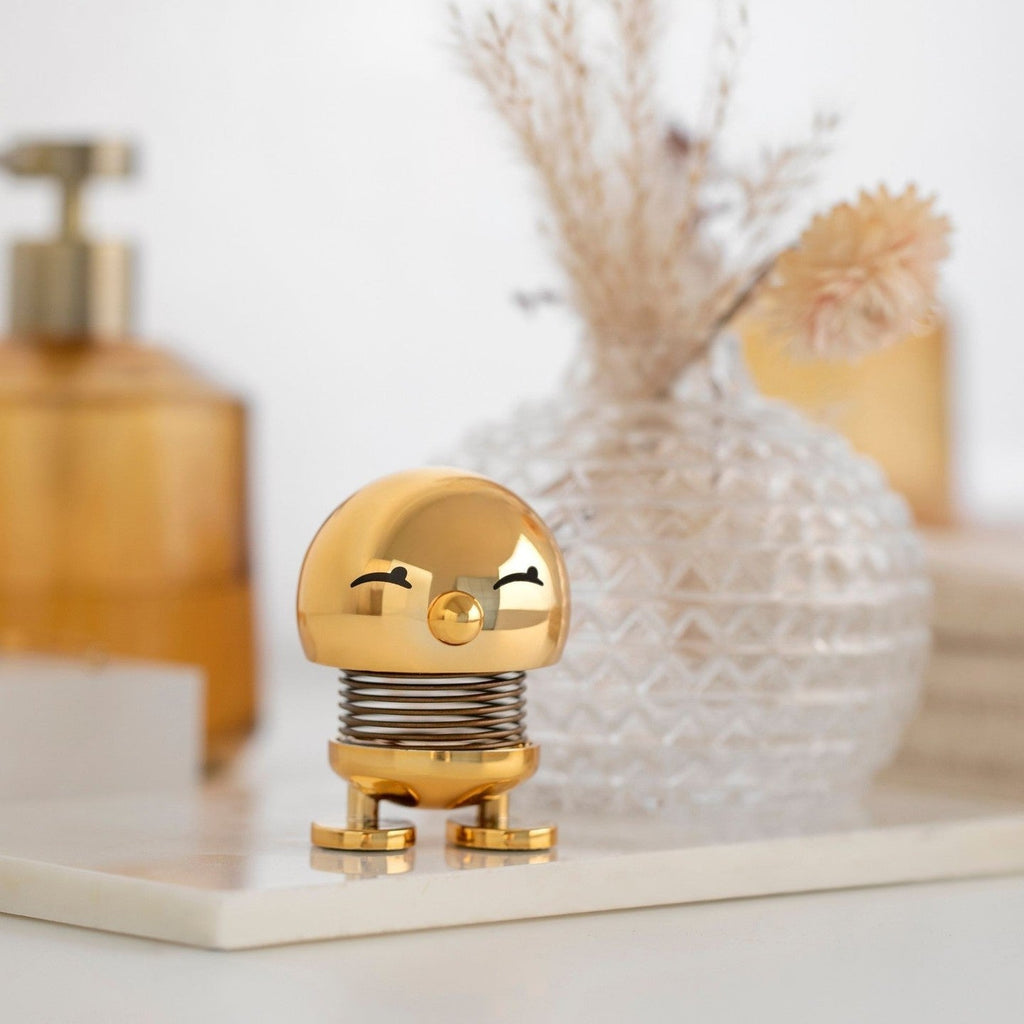 Gold spring toy with a face on a shelf with decorative items