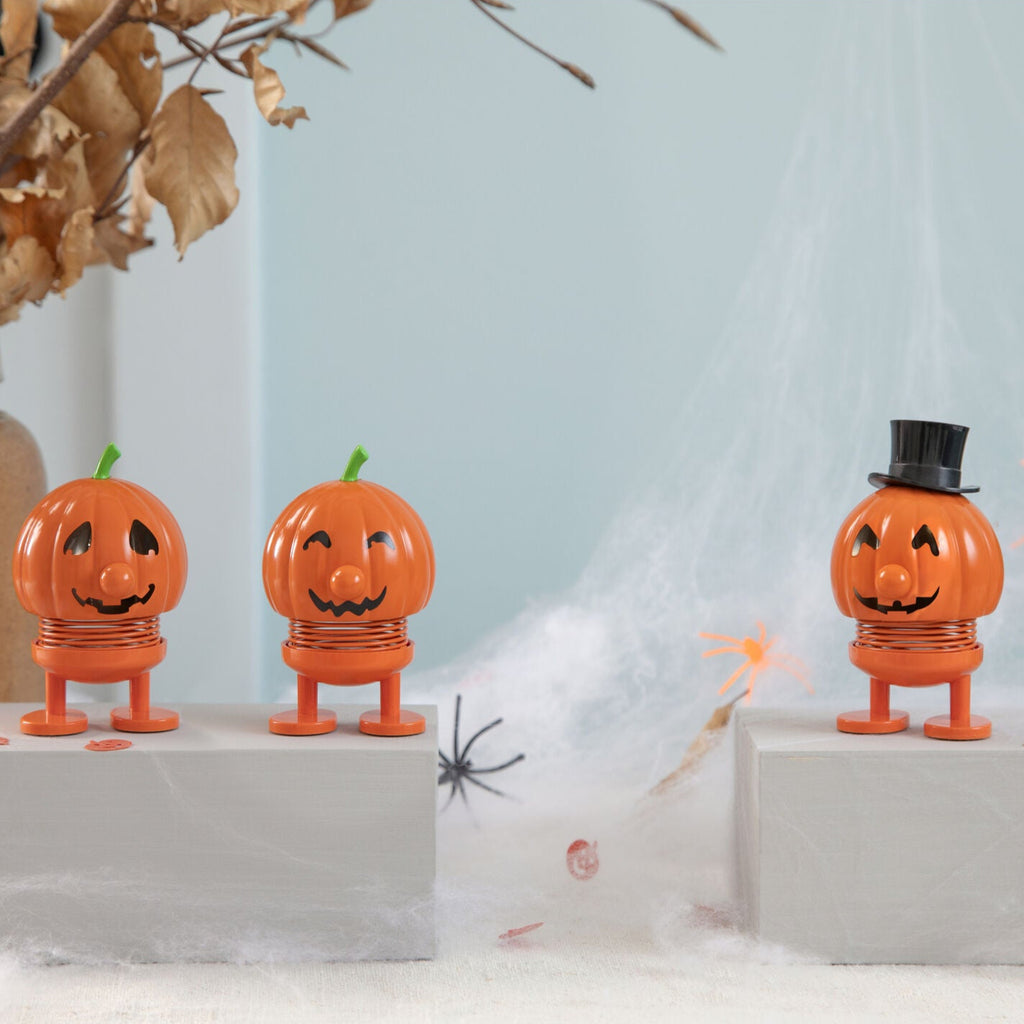 Three orange jack-o'-lantern toy figures on white stands with a light blue background.