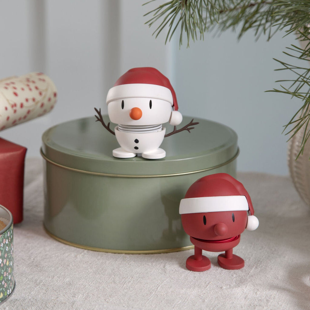 Decorative Christmas tin with a snowman figure and a red Santa Claus figure on a festive background.