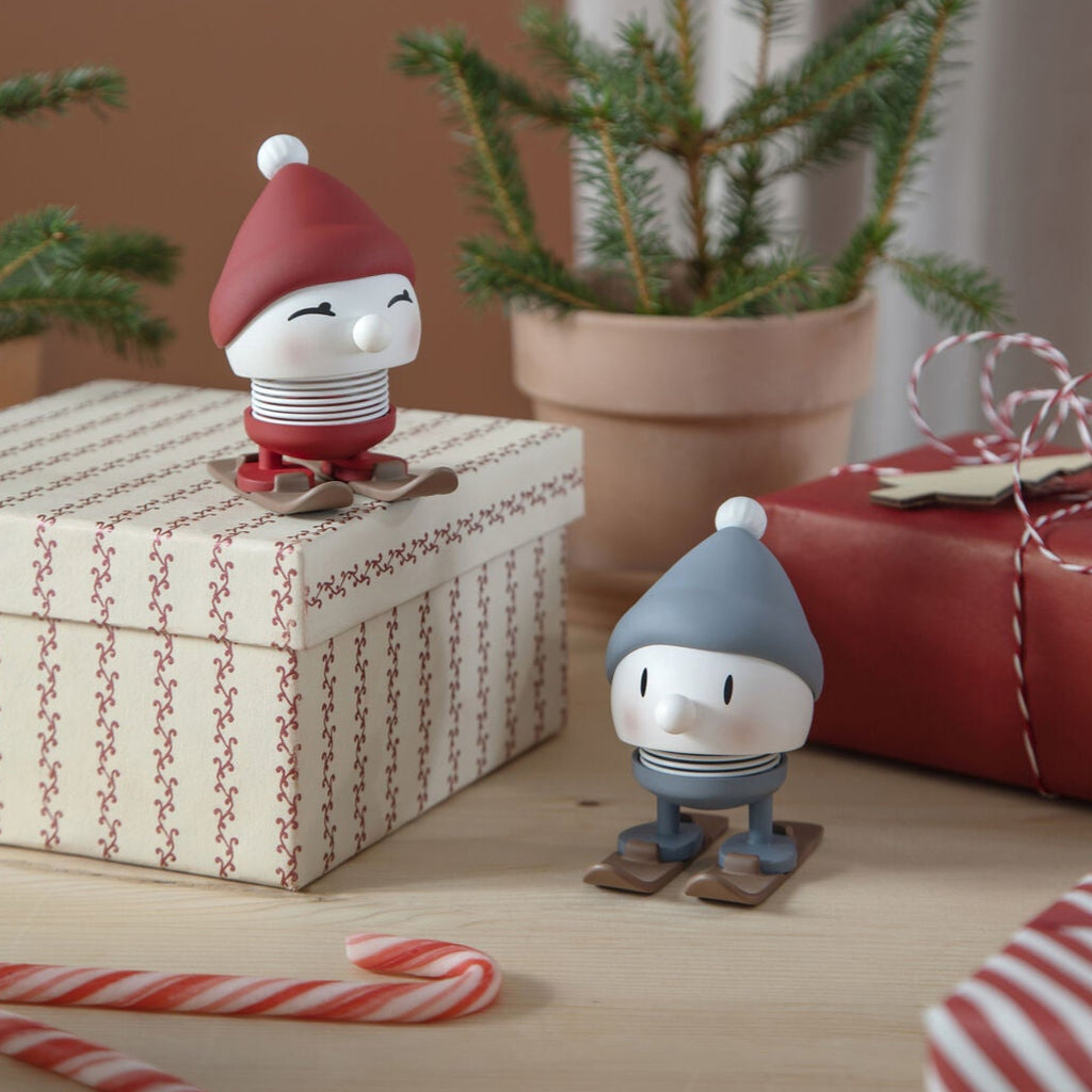 Two small figurines on a surface with Christmas decorations including candy canes and a small tree.