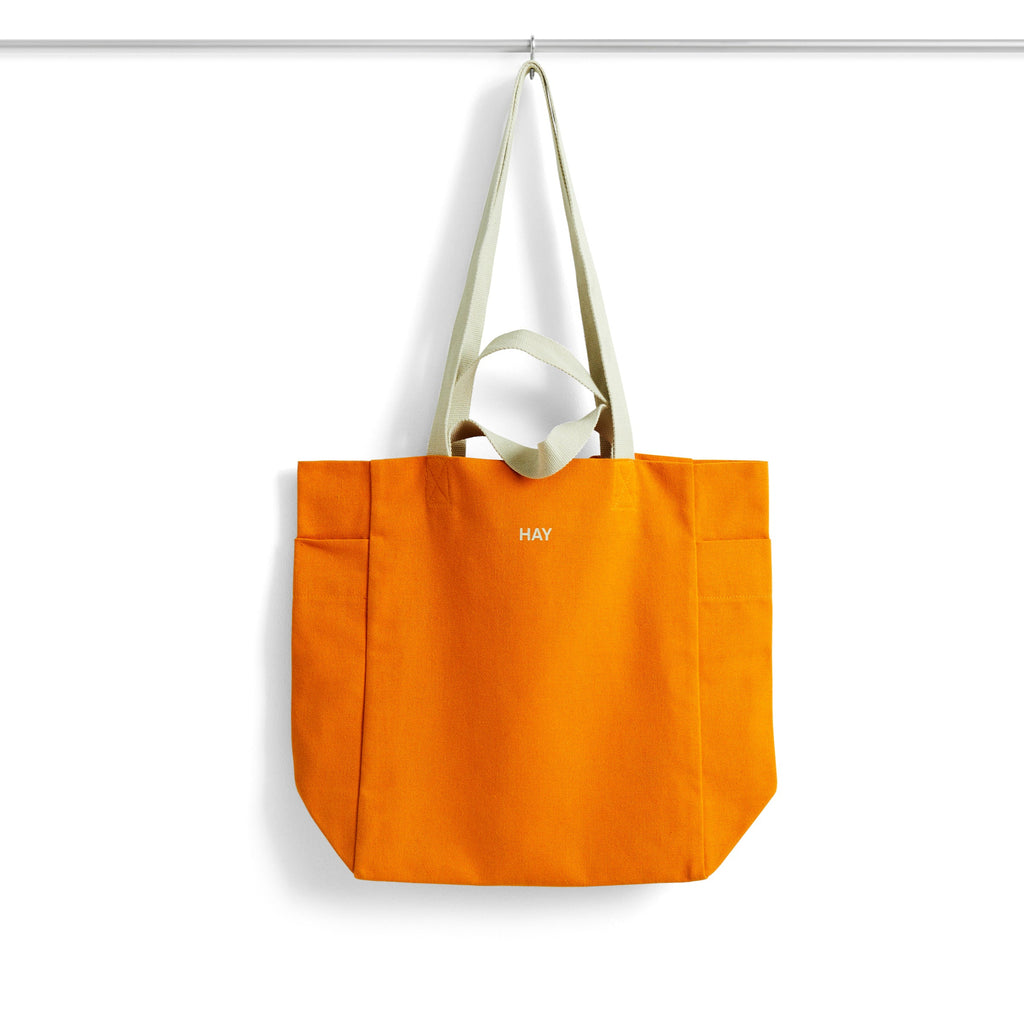 Orange tote bag with white handle on a white background
